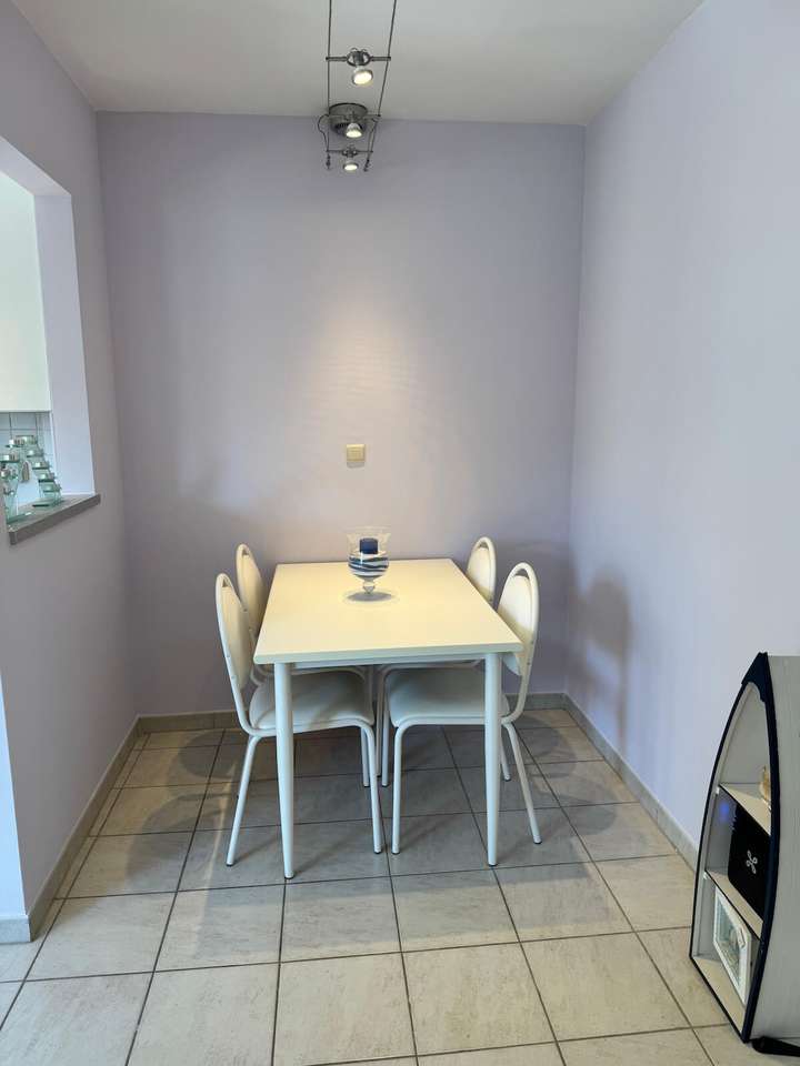 Coin repas avec table blanche moderne et quatre chaises dans l’appartement de vacances Charm 202 à la mer