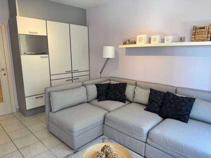 Salon avec canapé d’angle et grands rangements intégrés dans l’appartement de vacances Charm 202 à la mer